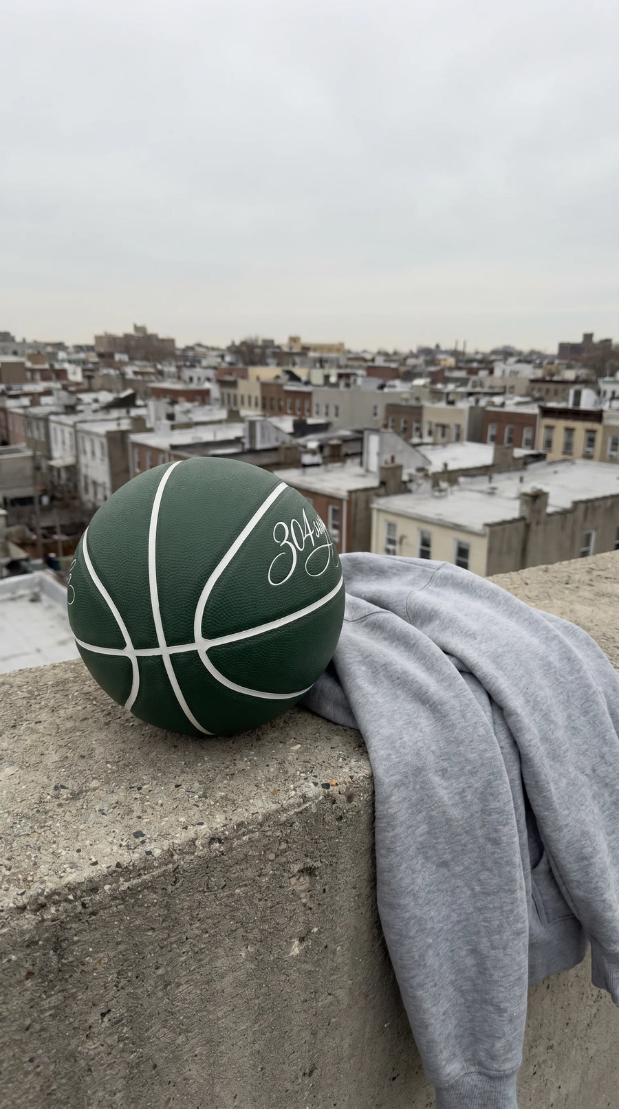 Grüner 304 Basketball auf Rooftop-Ledge mit Hoodie, Lifestyle